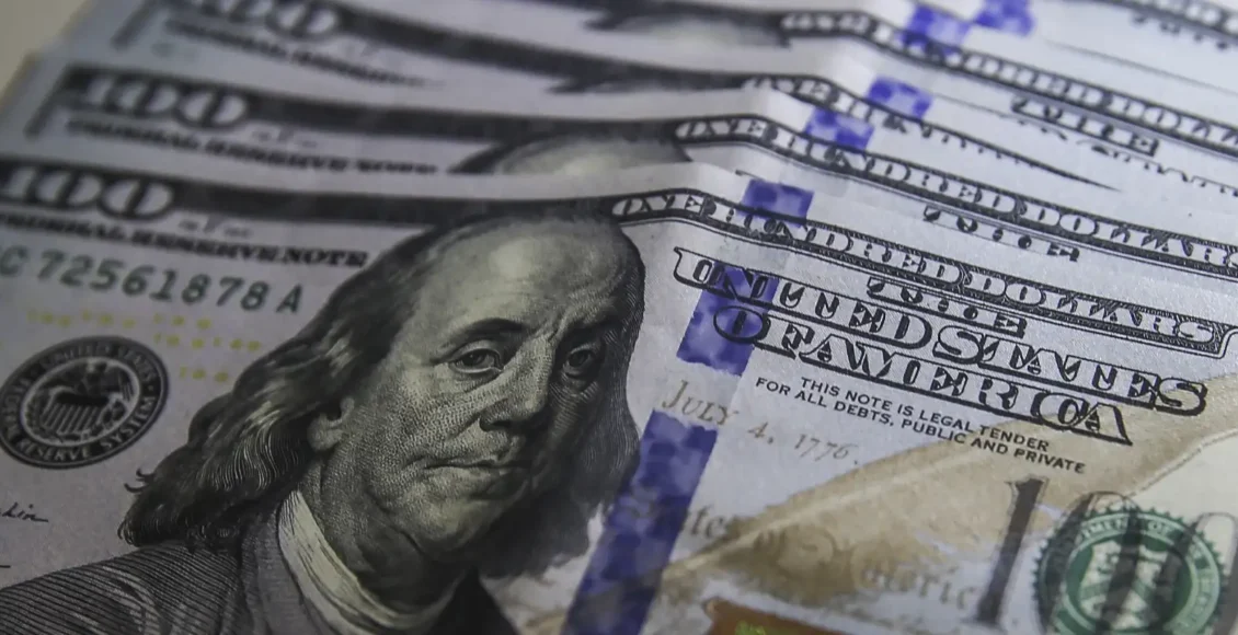 Cédulas de dólar e moedas de real, símbolo da variação cambial